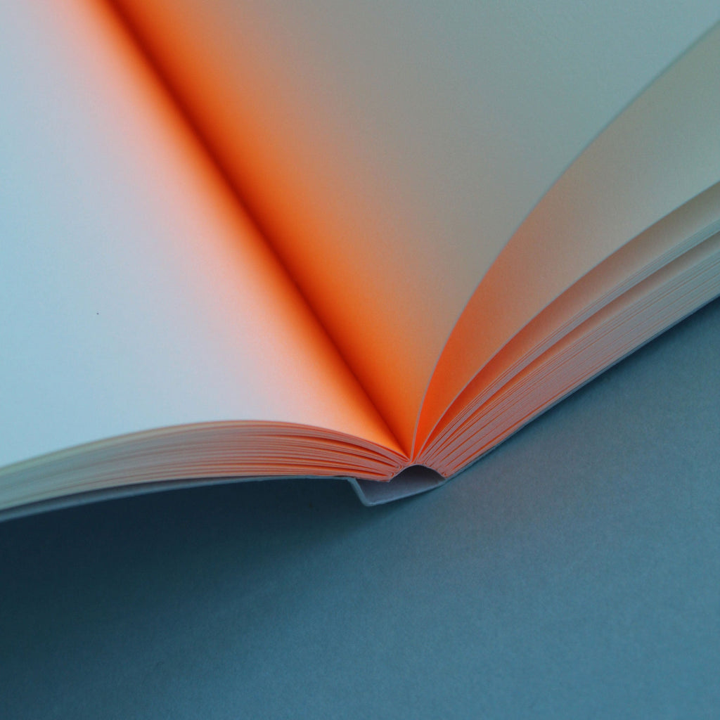 Open book with neon orange pages on a light blue background