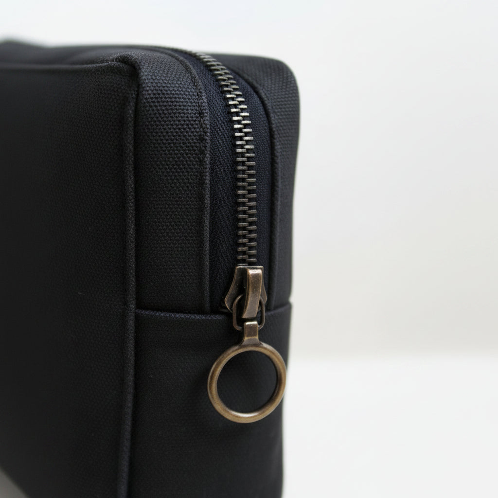 Black pouch with a brass riri zipper on a white background