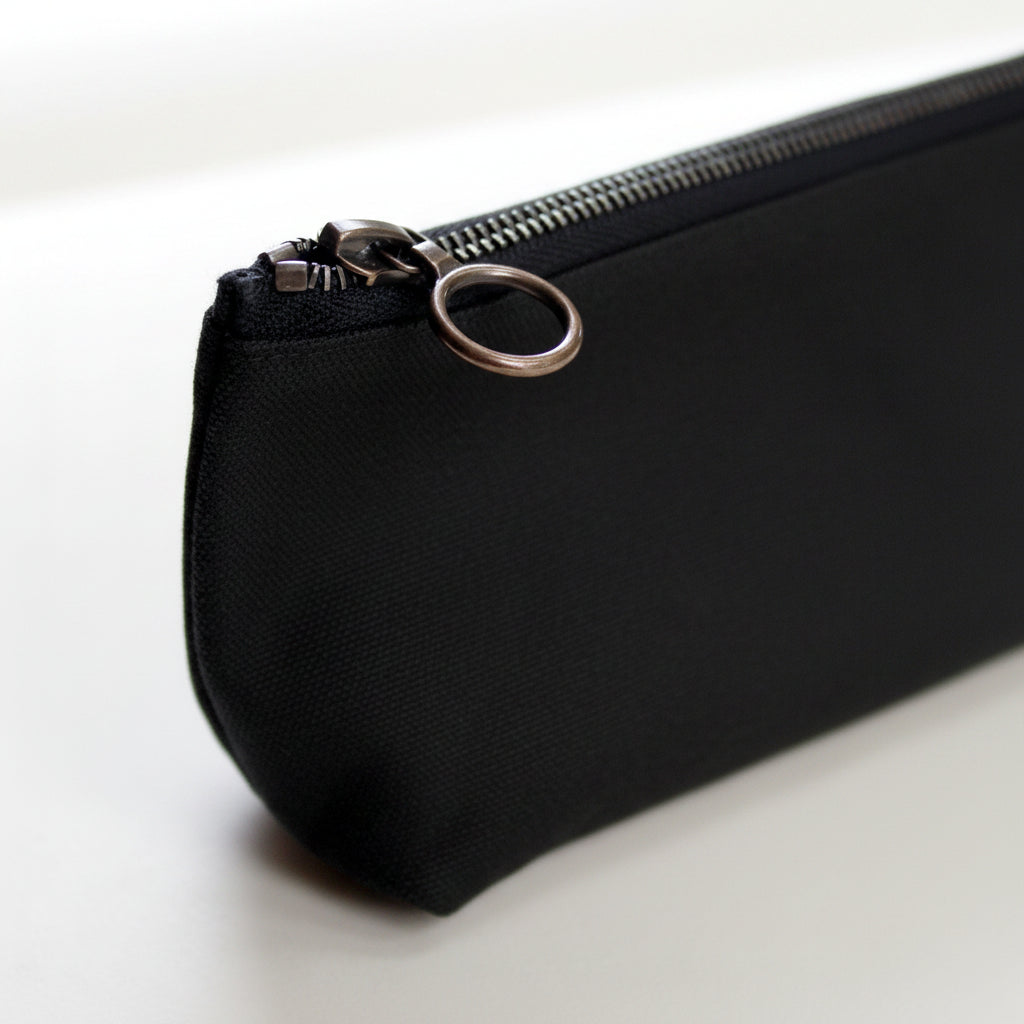 Black pencil case with a black and brass zipper on a white background