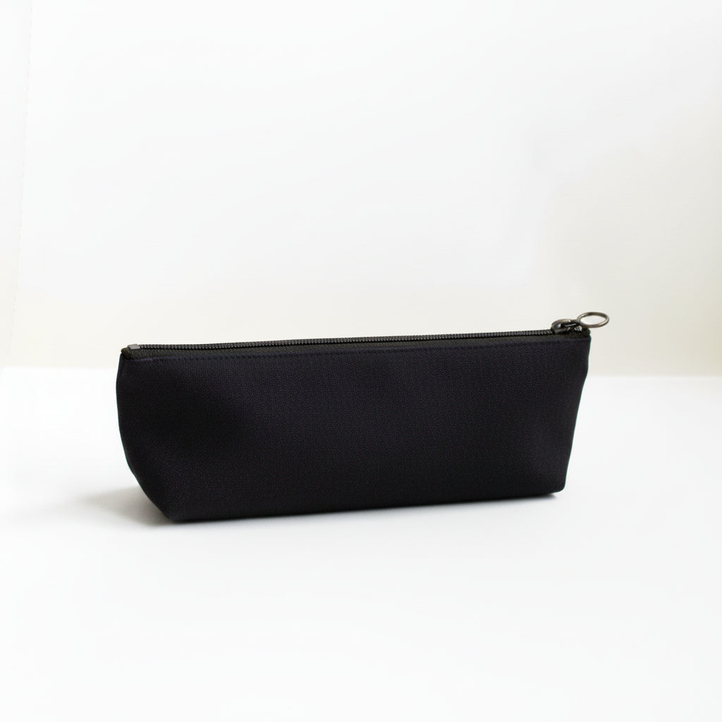 Black canvas pencil case with an antique brass zipper on a white background